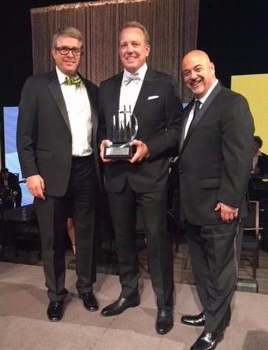 Jon Kinning, COO, Rick Kinning, CEO (holding award), and Marc Paolicelli, CCO.